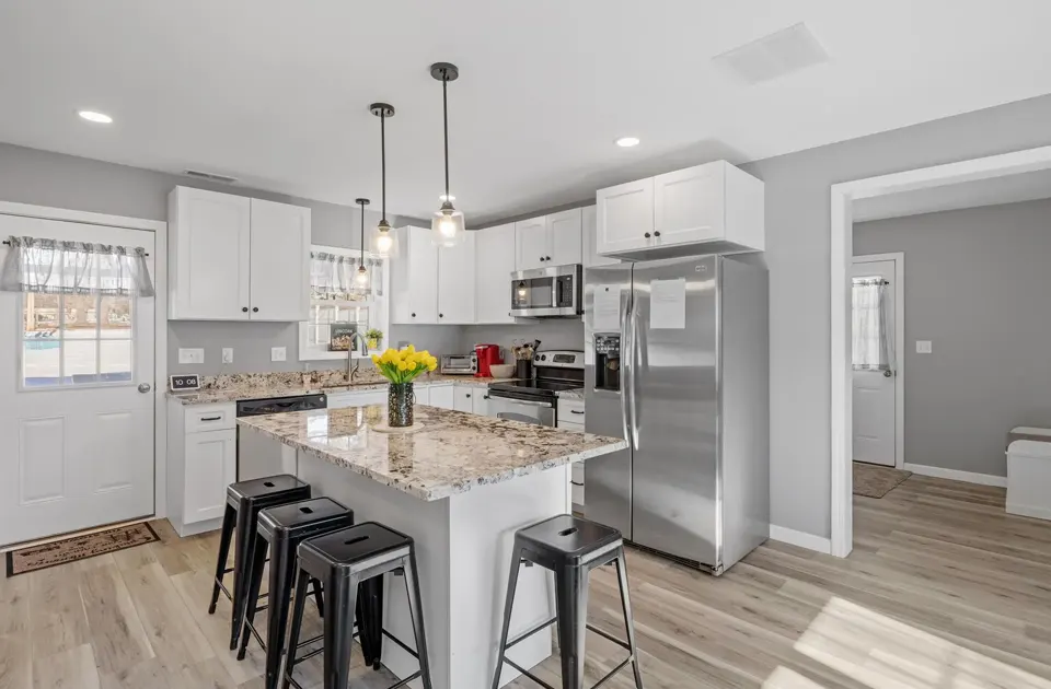 Bright kitchen remodel with white cabinets, granite island, and stainless steel appliances