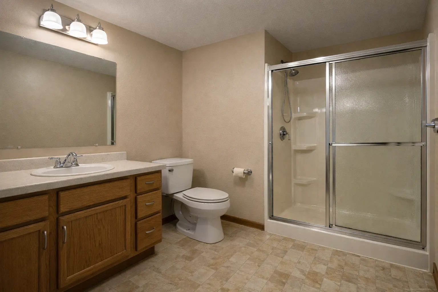 Outdated basement bathroom with oak vanity and sliding shower door