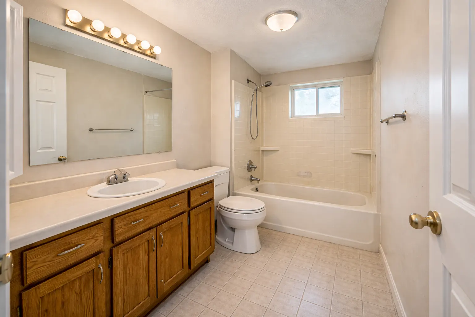 Outdated bathroom with oak vanity and tub shower combo
