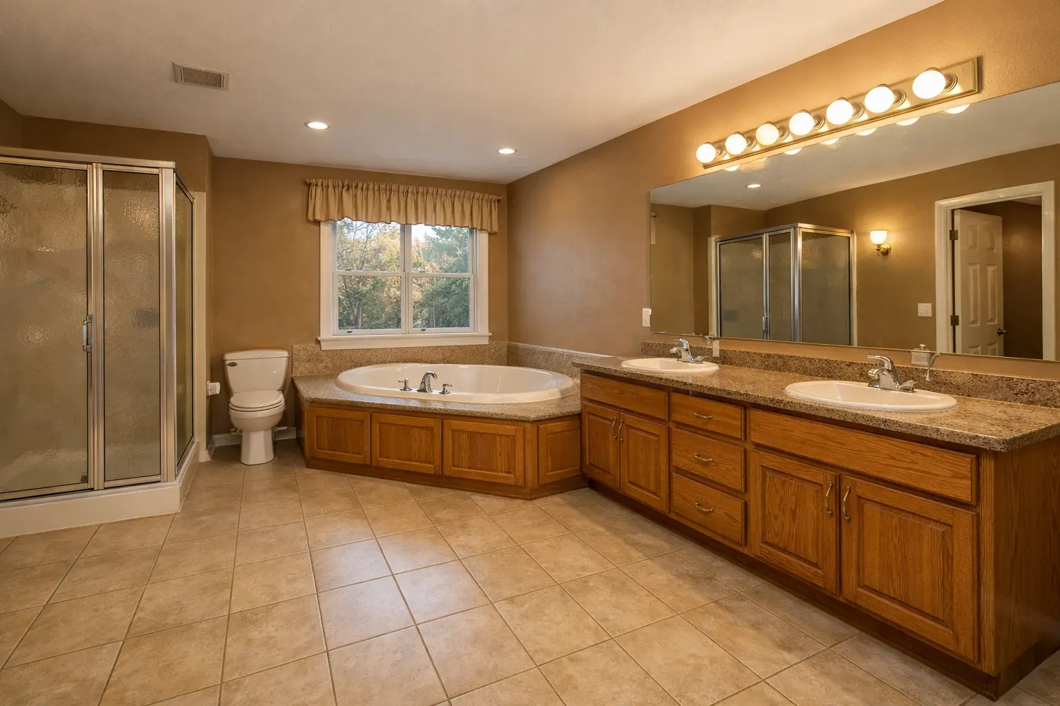 Large outdated bathroom with built-in tub and wood vanity