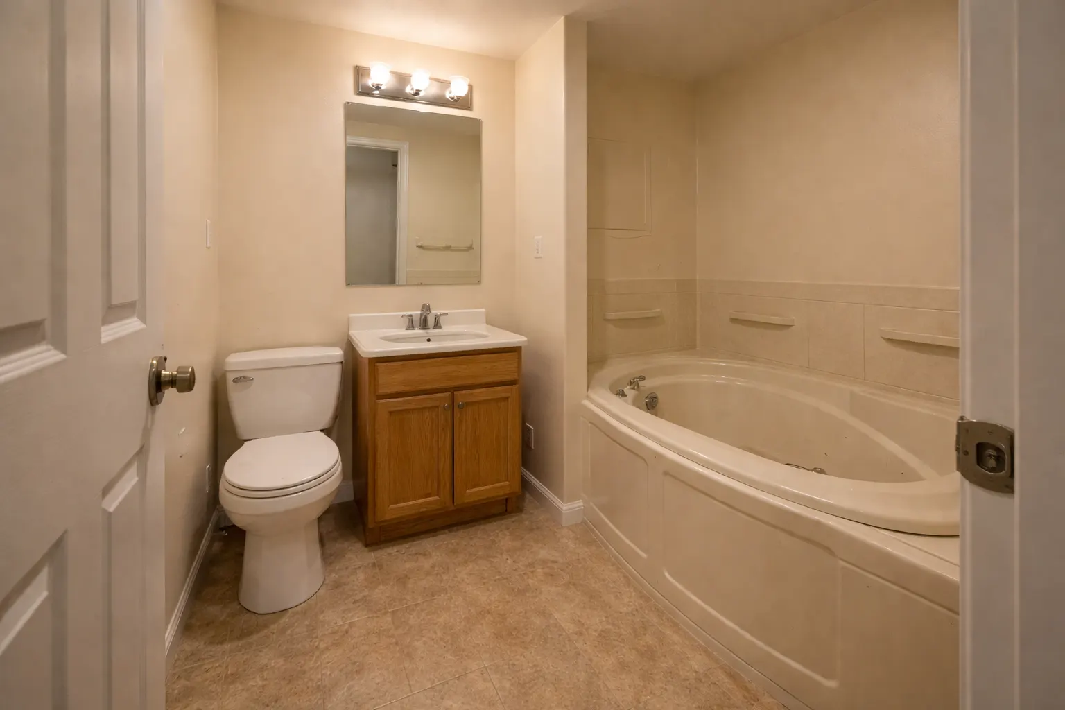 Small outdated bathroom with corner tub and basic vanity