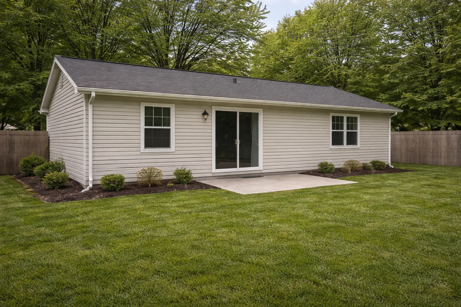 Backyard view of ranch home with sliding door and concrete patio
