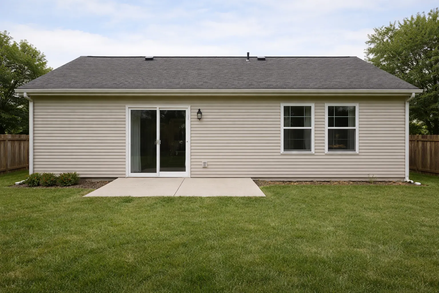 Plain backyard exterior with sliding door and small concrete patio