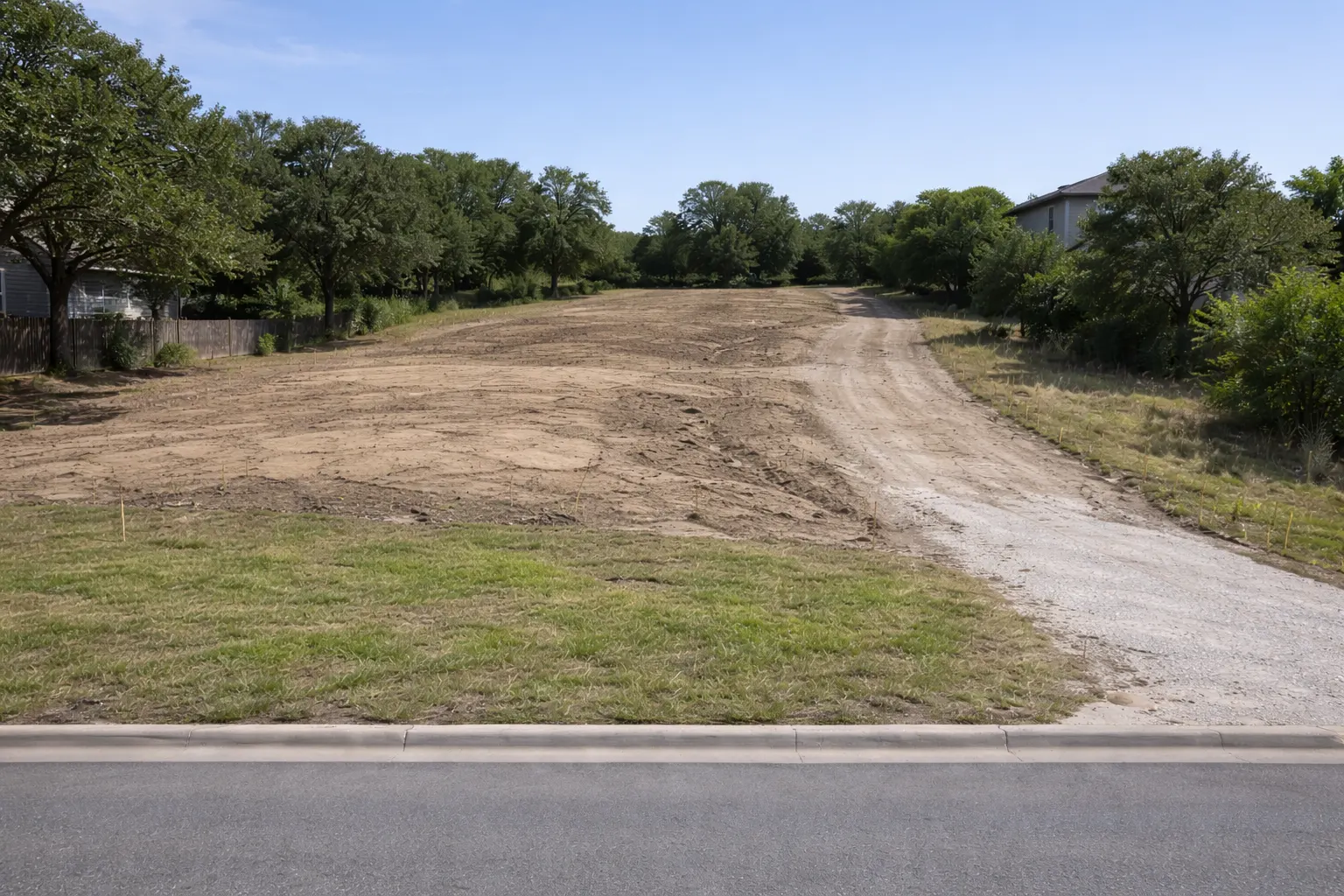 Sloped residential construction lot with dirt driveway access and grading